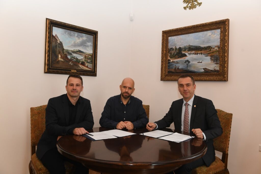 zdjęcie przedstawia siedzącego Rektora PK z przedstawicielami firmy EX7